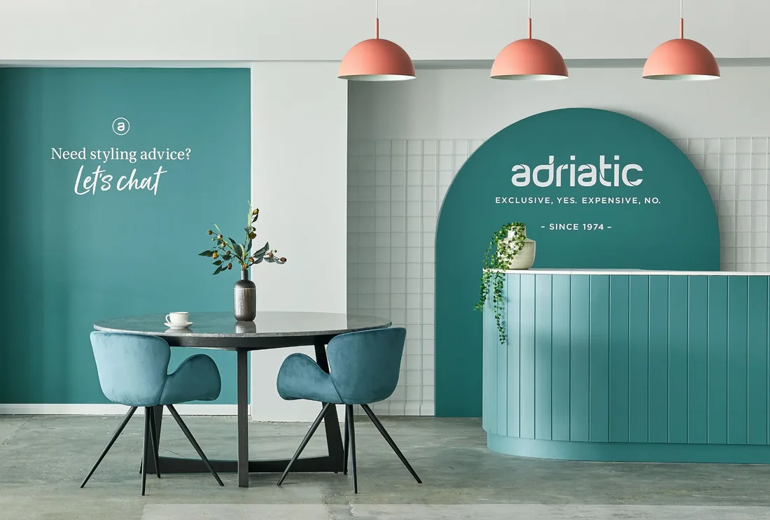Adriatic Furniture showroom interior with teal walls, dining setting and reception counter
